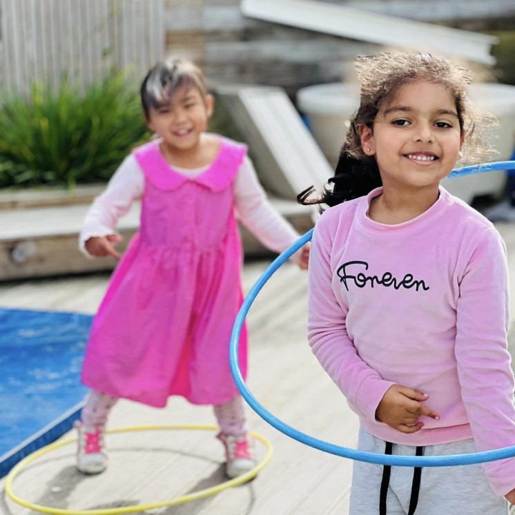 Two friends hula hooping outside at Busy Bees Alfriston Road