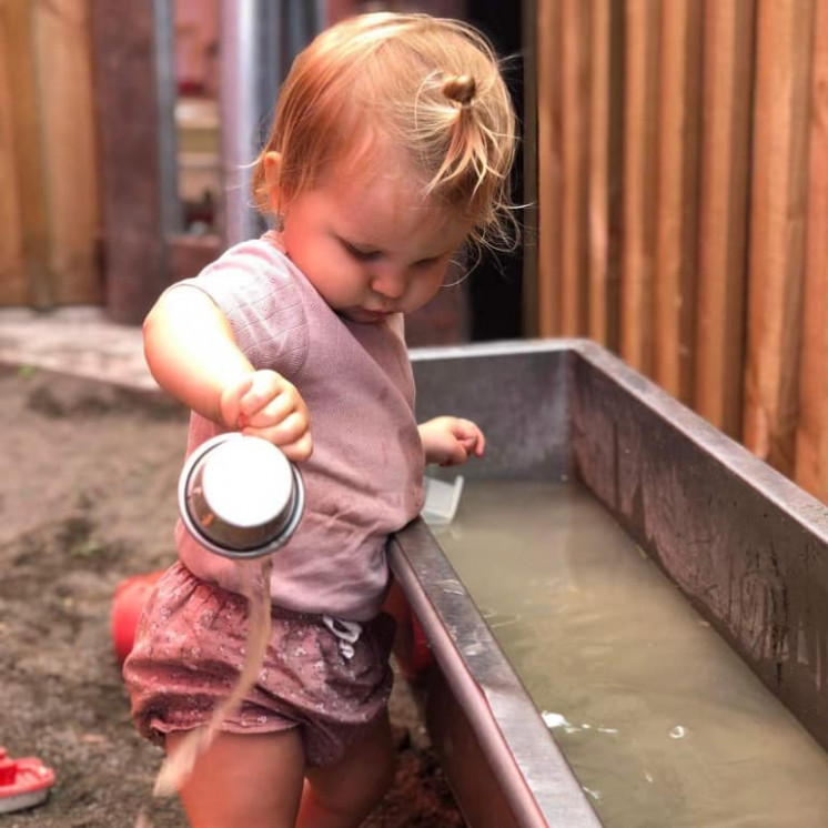 Little girl doing water play outside at Busy Bees Church Street early childhood learning centre