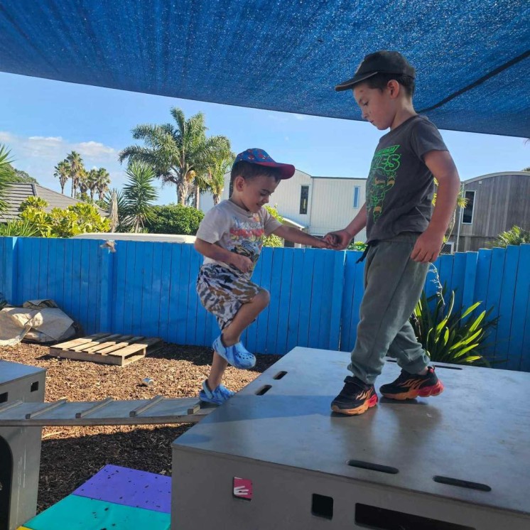 Coopers Beach boys helping each other on the playground