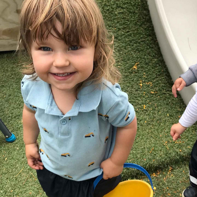 Little boy helping to harvest the peaches at Busy Bees Frimley