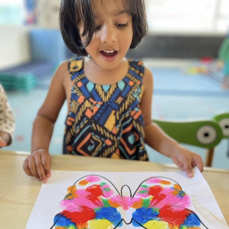 Girl amazed at her butterfly art paint creation at Busy Bees Mount Wellington childcare