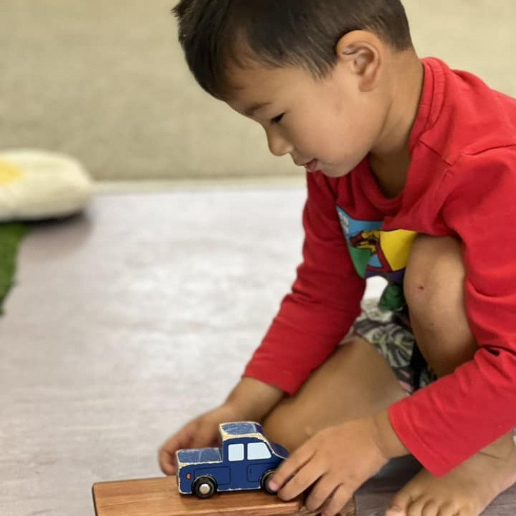 Boy enjoying playing with cars and transporting toys at Busy Bees Ormiston Road