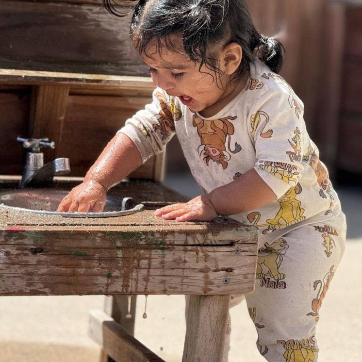 Little girl outside playing with water in a sink at Bust Bees Te Rapa