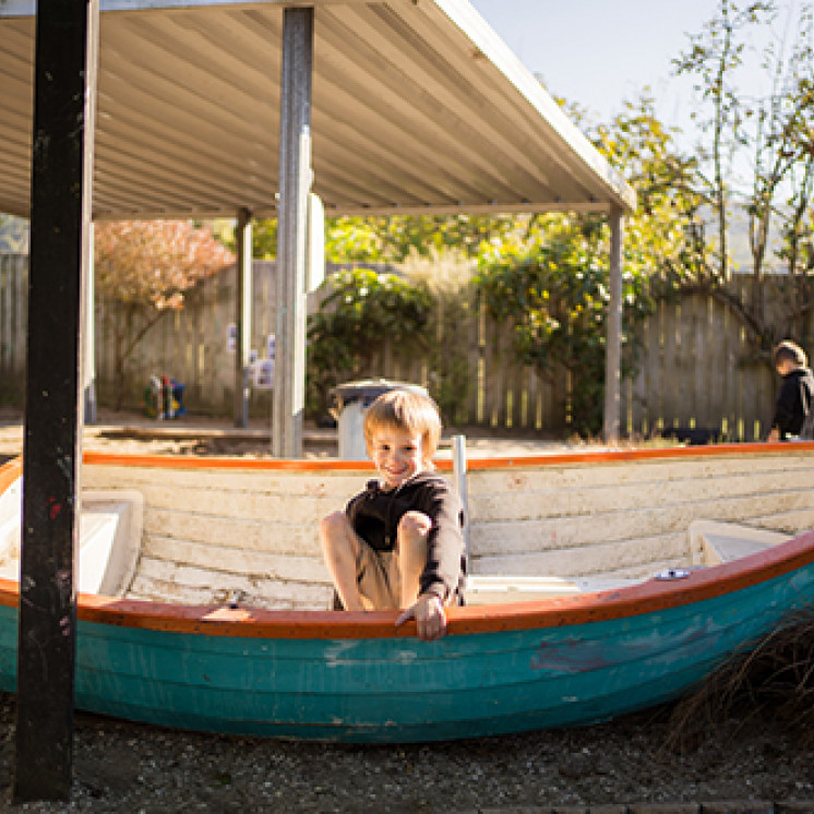 Little boy hiding in boat at Busy Bees Western Heights